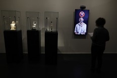 A woman watches a video installation of a man using emojis to communicate, at the exhibition 'Emoglyphs: Picture-Writing from Hieroglyphs to the Emoji' at the Israel Museum in Jerusalem, on December 19, 2019. 