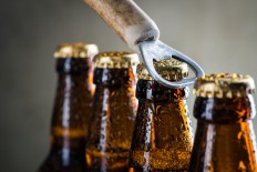 Brown ice cold beer bottles with water drops and old opener