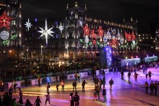 People skate on an acrylic rink placed in the Zocalo square with the City Hall showing Christmas decorations in the background in Mexico City on December 17, 2019.