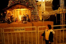 A girl looks at an artwork showing a nativity scene made of olive wood at Manger Square in Bethlehem in the Israeli-occupied West Bank on December 17, 2019. 