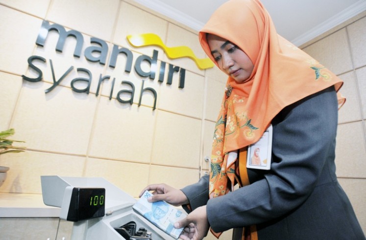 A teller counts money at a Mandiri Sharia Bank branch office in Menteng, Central Jakarta, in this file photo.