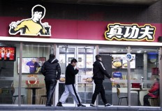 People walk past the restaurant Real Kung Fu, or Zhen Gongfu in Mandarin, run by fast food chain Kungfu Catering Management, in Beijing on December 26, 2019. Shannon Lee's Bruce Lee Enterprises is suing restaurant chain Kungfu Catering Management of having used her late father's image for 15 years in a logo without paying intellectual property rights.
