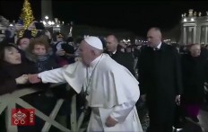 A frame grab taken from a handout video made available by Vatican Media on January 1, 2020 shows a lady (L) grabbing at Pope Francis' hands as he greets Catholic faithful as he arrives to celebrate New Year's Eve mass in Vatican City on December 31, 2019. 