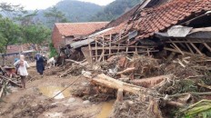 Residents walk by ruined houses damaged by flooding and landslides in Sukamaju hamlet, one of 11 hamlets in Sukajaya district most hard-hit by the disaster. More than 4,000 Sukajaya residents have been displaced and more than 400 houses heavily damaged by floods and landslides, which also claimed at least six lives in the district. 