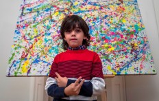 7-year-old German artist Mikail Akar poses in front of a limited print edition of his 'Champi' painting, prior to the opening of his 'Manus 11' exhibition in Berlin on December 13, 2019. 