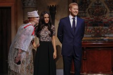 Tourists pose next to wax sculptures of Meghan Markle and Prince Harry as they attend a royal wedding watch party at the Madame Tussauds wax museum on May 19, 2018 in New York.