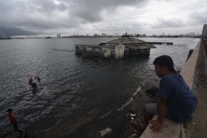 Children play in a flooded area of Muara Baru, Penjaringan, North Jakarta on Jan. 13. The coastal area suffers land subsidence in addition to rising tidal waves.