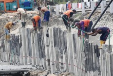 Construction workers install sheet piles on Oct. 17, 2018 along 1,600 meters of the Grogol River in Palmerah, West Jakarta as part of a project to normalize the river.