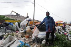 Local scavenger Rosani Saalih, 53, poses amid piles of waste at the Cipayung dumpsite in Depok, West Java, on Jan. 15.