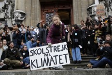 Seventeen-year-old Swedish climate activist Greta Thunberg (center) holds a placard reading 'School strike for Climate' during a climate strike against governmental inaction towards climate breakdown and environmental pollution in Lausanne, on January 17, 2020. 