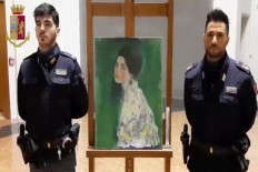 This file image grabbed from a video taken in Piacenza on December 11, 2019 and handout by the Italian State Police on December 12, 2019 shows Police officers standing by a painting stolen over 20 years ago and for which initial indications suggest that it was painted by Austrian painter Gustav Klimt, found by chance in the gardens of a museum in Piacenza, northern Italy. 
