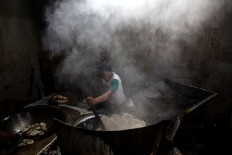 A worker fries crackers in a large wok. JP/Afriadi Hikmal