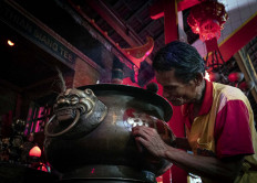 A temple caretaker cleans an incense jar. JP/Bismo Agung