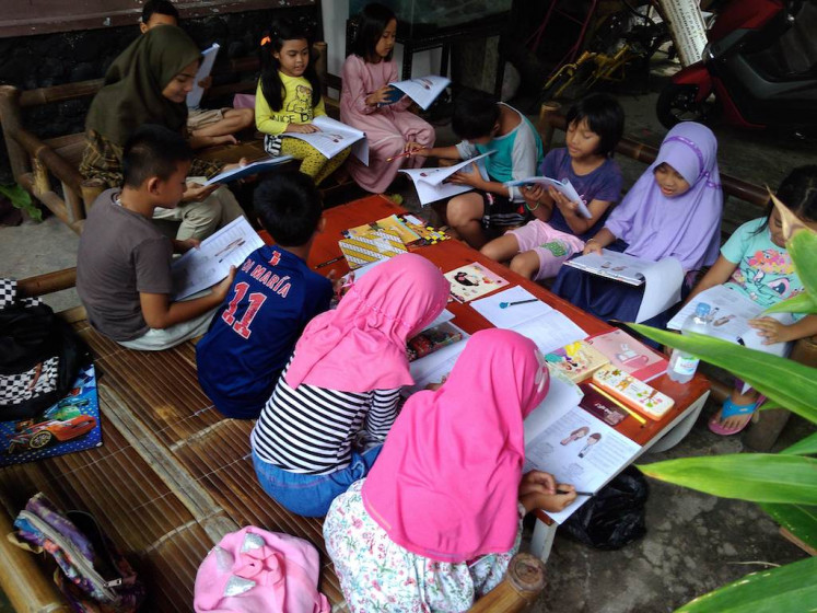 Children learn English with Irmanda Sri Amri, a student of Jakarta State University (UNJ) and volunteer at the Sempur English Camp in Bogor, West Java, on Jan. 21. 