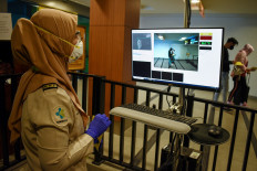 An Indonesian health official checks a screen while using a thermal scanner for passengers arriving amid a deadly virus outbreak which began in the Chinese city of Wuhan, at the Husein Sastranegara airport in Bandung on January 27, 2020.