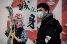 A man wearing a protective mask to help stop the spread of a deadly virus which began in Wuhan, stands outside Beijing railway station in Beijing on January 27, 2020. - China on January 27 extended its biggest national holiday to buy time in the fight against a viral epidemic and neighbouring Mongolia closed its border, after the death toll spiked to 81 despite unprecedented quarantine measures. 