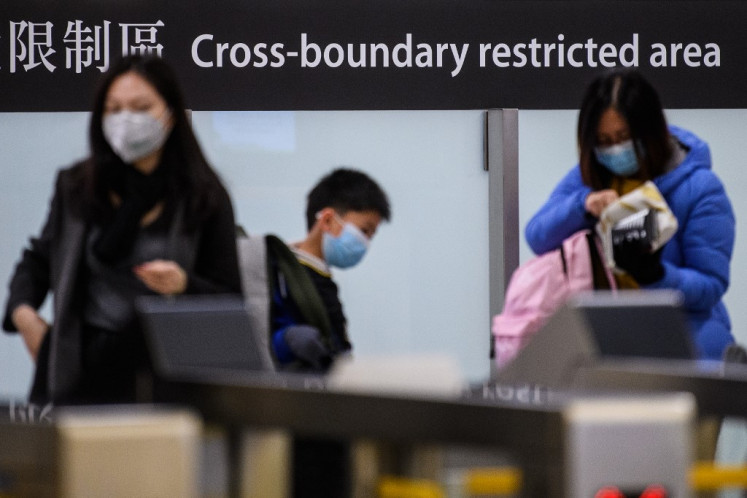 Commuters arriving in Hong Kong wear facemasks as they pass the cross boundary restricted area inside the high-speed train station connecting Hong Kong to mainland China during a public holiday in celebration of the Lunar New Year in Hong Kong on January 28, 2020, as a preventative measure following a virus outbreak which began in the Chinese city of Wuhan. - China on January 28 urged its citizens to postpone travel abroad as it expanded unprecedented efforts to contain a viral outbreak that has killed 106 people and left other governments racing to pull their nationals from the contagion's epicentre. 