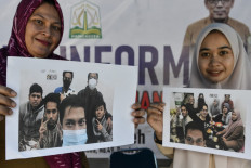Staff members hold photographs of Indonesian students from Aceh trapped in the Chinese city of Wuhan following a lockdown due to a deadly virus outbreak, at an information booth in Banda Aceh on January 28, 2020.