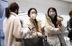 Passengers wear face masks as they stand with their luggage after arriving off of a flight at Terminal 5 of London Heathrow Airport in west London on January 28, 2020.