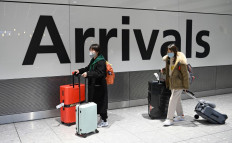 Passengers wear face masks as the push their luggage after arriving from a flight at Terminal 5 of London Heathrow Airport in west London on January 28, 2020. - Chinese President Xi Jinping said Tuesday the country was waging a serious fight against the 