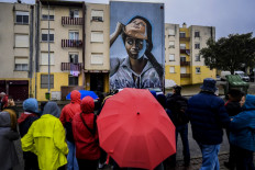 Visitors watch a mural by Portuguese-Angolan artist Nomen during a guided visit to Quinta do Mocho neighborhood in Sacavem, outskirts of Lisbon, on November 11, 2019. 
