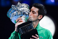 Serbia's Novak Djokovic kisses the Norman Brooks Challenge Cup trophy following his victory against Austria's Dominic Thiem in their men's singles final match on day fourteen of the Australian Open tennis tournament in Melbourne early on February 3, 2020. 
William WEST