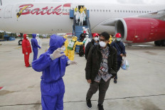 This handout photo taken and released by the Indonesian Embassy on February 2, 2020,  shows officials in full protective gear with Indonesian students as they disembark upon the arrival at Hang Nadim international airport in Batam, following their evacuation from the Chinese city of Wuhan due to the deadly SARS-like virus. - The coronavirus outbreak has killed more than 300 people and infected more than 14,000 in mainland China and beyond, forcing governments around the world to take drastic measures. 