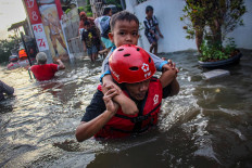 An Officer rescues a flood-affected resident in Periuk Damai, Tangerang city, Banten, on Feb. 3. The flooding was caused by the collapse of an embankment in the area because of heavy rainfall since morning.