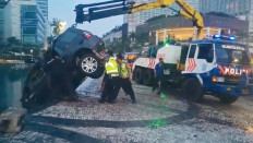 Police officers evacuate a vehicle that crashed into the Hotel Indonesia traffic circle's pond in Jakarta on Wednesday.