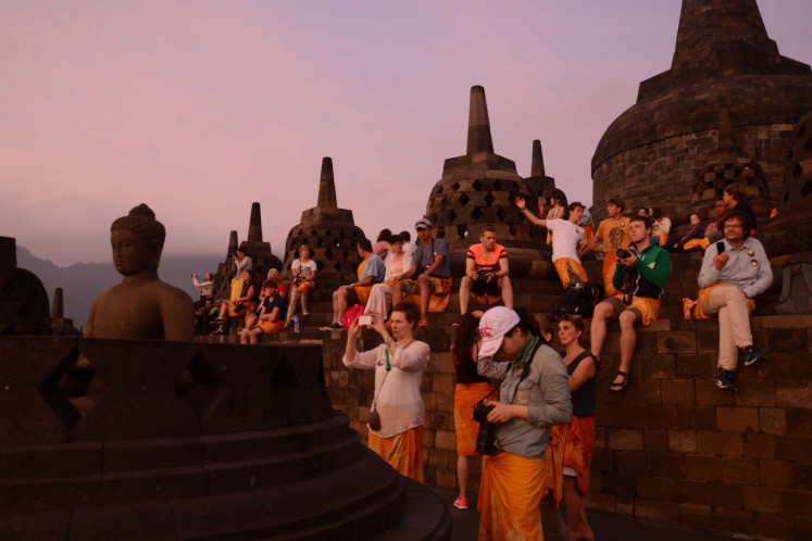 Domestic and foreign visitors watch the sun rise on July 23, 2014, from the summit of Borobudur Temple in Magelang regency, Central Java.