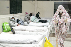 This photo taken on February 5, 2020 shows a patient (R) covered with a bed sheet at an exhibition centre converted into a hospital as it starts to accept patients displaying mild symptoms of the novel coronavirus in Wuhan in China's central Hubei province. - China scrambled to find bed space for thousands of newly infected patients on February 6, as the toll from a deadly new virus jumped again with more than 28,000 people known infected nationwide and 563 deaths. (Photo by STR / AFP) / China OUT
