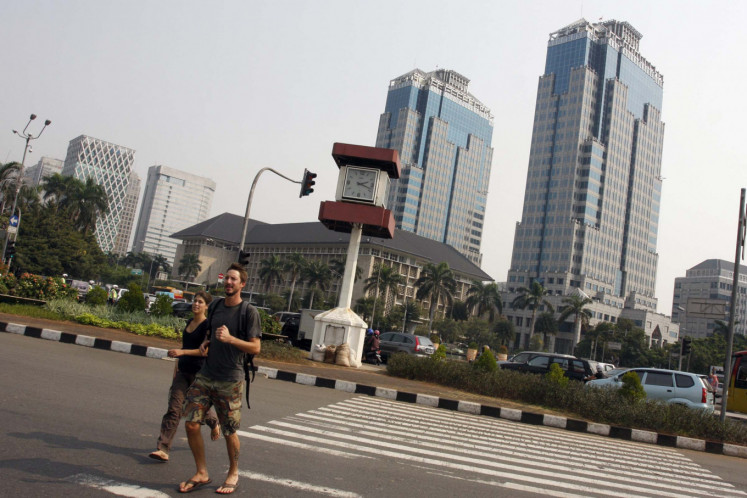 Two expatriate tourists crossed the Thamrin road in front of the Bank Indonesia building, Jakarta, Thursday, July 6, 2009. 