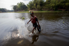 Another day: A treasure hunter walks to the riverbank after searching for valuables in its depths. JP/ Sigit Pamungkas