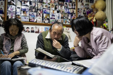 This photo taken on Dec.17, 2019 shows matchmaker Zhu Fang (center) talking to a woman seeking his advice (right) in his house in Beijing. - For almost 50 years Zhu Fang has been one of Beijing's most popular matchmakers, and even now -- aged 75 -- he remains in as much demand as ever. 