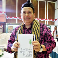 Author Bambang Supriyanto poses with his book, "Catatan dari Tepi Hutan" (Notes From the Forest’s Edge) during its launch in Jakarta