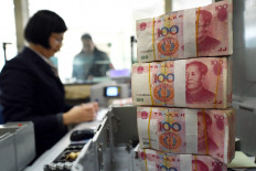 An employee counts 100-yuan (15 USD) banknotes at a bank in Lianyungang, in eastern China's Jiangsu province on January 7, 2016. 