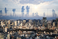 Reflections of people are seen on glass from a rooftop viewing area showing Tokyo's east side on February 8, 2020.
