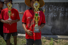 A farmer of the winning team smiles as he holds the first-place trophy. JP/Ali Lutfi