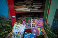 Children look at the covers of donated books on religion, crafts and real-life school experiences at a book-sharing box in the Jatipulo literacy kampung. JP/Afriadi Hikmal