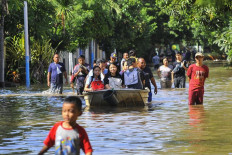 Residents take to a boat during flooding in Pulomas, East Jakarta on Sunday.