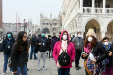 Tourists wearing protective masks visit Venice on February 25, 2020, during the usual period of the Carnival festivities which have been cancelled following an outbreak of the COVID-19 novel coronavirus in northern Italy. 