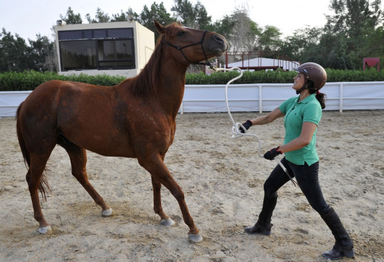 Saudi Dana al-Gosaibi trains a horse on March 1, 2017, in the Red Sea city of Jeddah. - The 35-year-old Saudi horse trainer dreams of opening her own stables to focus on 