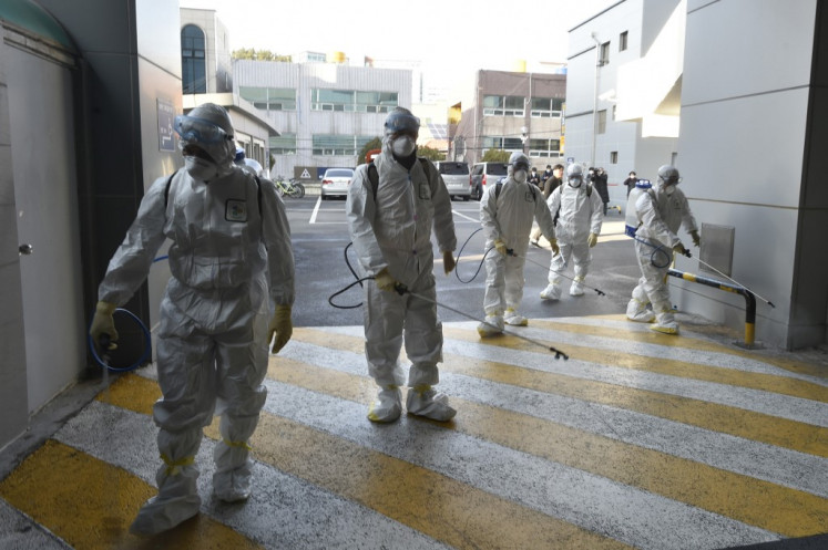 This handout picture taken on February 19, 2020 by Daegu Metropolitan City Namgu shows South Korean health officials wearing protective suit and spraying disinfectant in front of the Daegu branch of the Shincheonji Church of Jesus in the southeastern city of Daegu as about 40 new cases of the COVID-19 coronavirus confirmed after they attended same church services. - A cluster of novel coronavirus infections centred on a cult church in the South Korean city of Daegu leaped to 39 cases February 20, as the country's total spiked for the second successive day. 