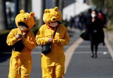 Visitors wearing protective face masks and Winnie the Pooh costumes, following an outbreak of the coronavirus, are seen outside Tokyo Disneyland in Urayasu, east of Tokyo, Japan February 28, 2020.  