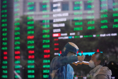 A worker in protective suit takes body temperature measurement of a woman inside the Shanghai Stock Exchange building, as the country is hit by the COVID-19 outbreak, at the Pudong financial district in Shanghai, China, on Feb. 28, 2020.