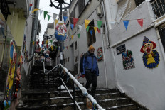 A pedestrian descends steps on a street decorated with carnival masks under snowfall in Thessaloniki on February 23, 2019. 