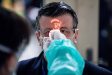 A worker screens the temperature of passengers arriving from Italy at Debrecen International Airport in Debrecen, Hungary, on Monday, Feb. 24, 2020. 