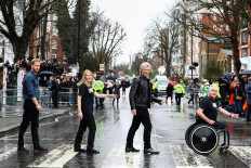 Britain's Prince Harry, Jon Bon Jovi and two choir members walk on the famous zebra crossing that The Beatles walked across, during a visit at Abbey Road Studios in London, Britain February 28, 2020. 