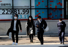 People wearing surgical masks walk past a screen showing Nikkei index outside a brokerage in Tokyo, Japan February 3, 2020. REUTERS/Kim Kyung-Hoon