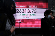 People wear protective masks as they walk past a panel displaying the Hang Seng Index during morning trading following the outbreak of the new coronavirus in Hong Kong, China March 2, 2020. REUTERS/Tyrone Siu